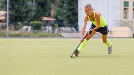 Young female field hockey player leading ball in attack. Image with copy spaceの写真素材