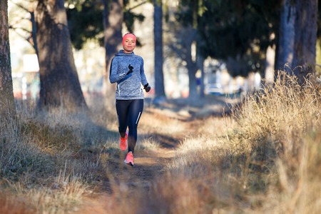 Young woman jogging on trail in autumn parkの写真素材