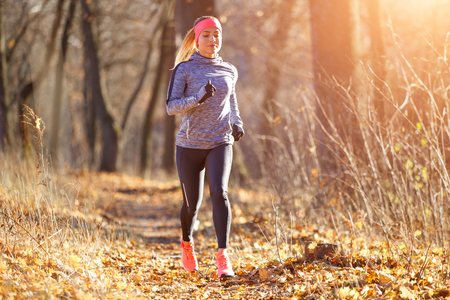 Young woman jogging on trail in autumn parkの写真素材