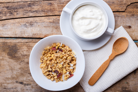 Healthy breakfast background. Muesli with yoghurt in bowl on wooden backgroundの写真素材