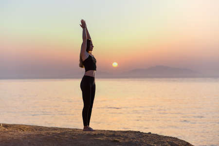 Young woman practicing yoga asana pose in the morning at the sea.の写真素材