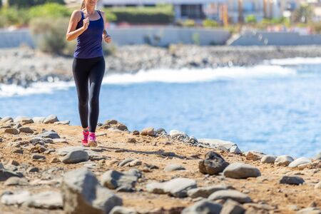 Young slim woman running near the sea in the morningの写真素材