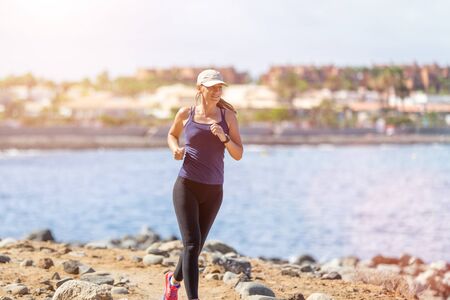 Young slim female runner near the sea jogging in the morning. Healthy lifestyle background with copy spaceの写真素材