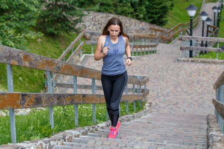 Young running woman ascending stairs in the morning