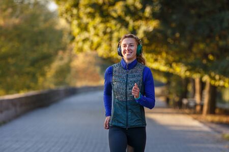 Happy girl jogging in autumn park in the morning.の写真素材