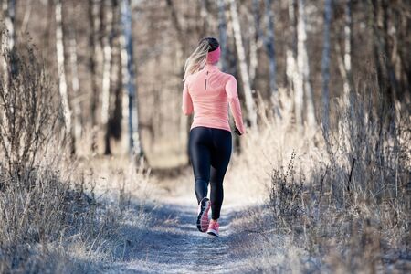 Back view of running girl in fall park in morningの写真素材