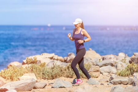 Young slim woman running near the sea in the morningの写真素材