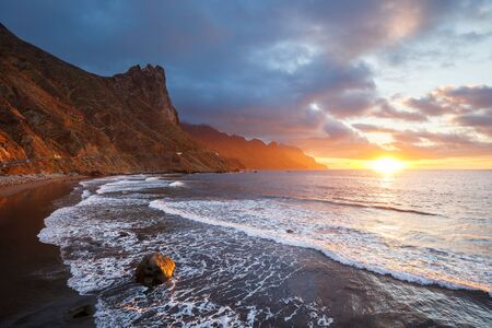 Sunset at the black beach of Tenerife in Atlantic oceanの写真素材