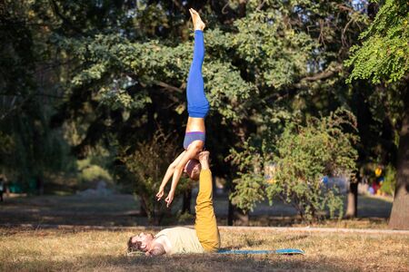 Acroyoga couple practising shoulder stand pose in the parkの写真素材