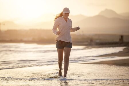 Young woman running at sunset on the La Tejita beach, Tenerifeの写真素材