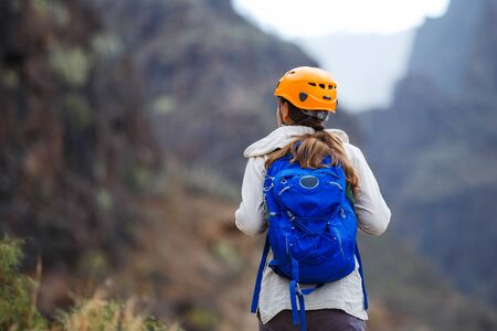 Young woman with backpack enjoying mountains on trekking trip in volcanic ravine on Tenerife, Spainの写真素材