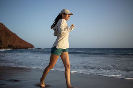 Young woman running at sunset on the La Tejita beach, Tenerifeの写真素材