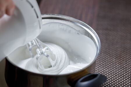 Woman whisking with mixer eggs whites with sugar preparing some dessertの写真素材