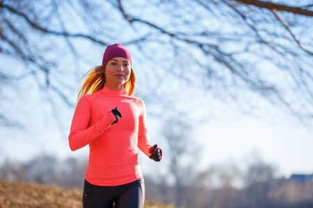 Young slim woman running in park in the morning.