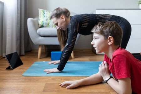 Small boy together with his mother practicing yoga at home during quarantineの写真素材