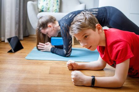 Small boy together with his mother practicing yoga at home during quarantine
