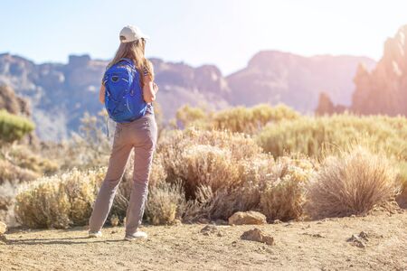Young slim travelling woman with backpack in mountains of Tenerife, Spain. Hiker girl in nature parkの写真素材