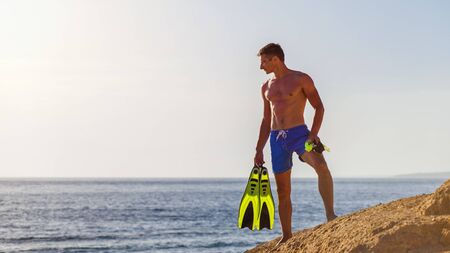 Young man with snorkelling equipment standing near the sea. Snorkelling on the vacationsの写真素材