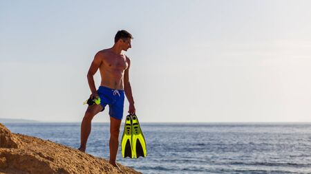 Young man with snorkelling equipment standing near the sea. Snorkelling on the vacationsの写真素材