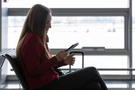 Young woman reading book waiting for the flight at the airportの写真素材