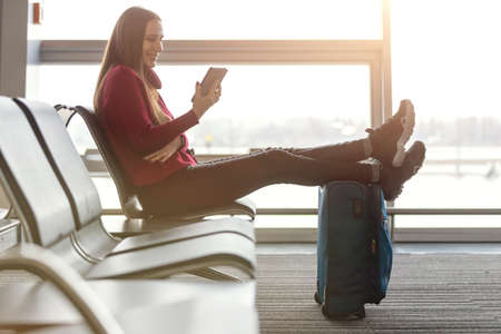 Young woman reading book waiting for the flight at the airportの写真素材