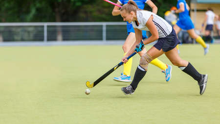 Young woman playing field hockey game on the pitch. Female field hockey game image with copy spaceの写真素材