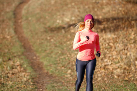 Sporty woman in sportswear jogging in park. Slim girl running on hillsの写真素材