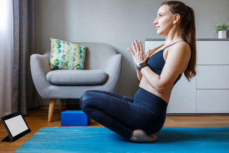 Young woman practicing online class yoga at home during quarantine.の写真素材