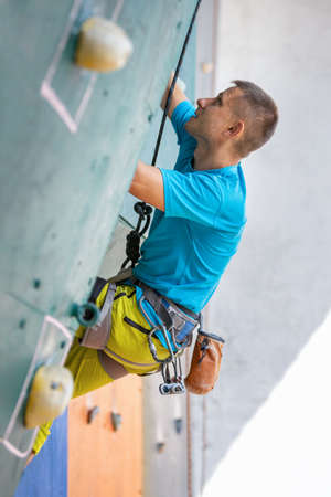 Young man climber on the training climbing wall