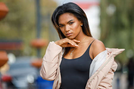 Young multiracial woman posing outdoors on fall day. Beautiful black girl standing on the streetの写真素材