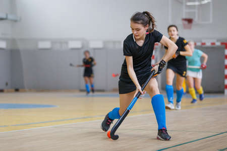 Young woman hockey player in attack at indoor hockey matchの写真素材