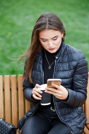 Young beautiful stylish woman using smartphone in the parkの写真素材