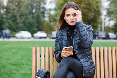 Young beautiful stylish woman using smartphone in the parkの写真素材