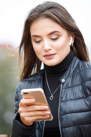Young beautiful stylish woman using smartphone in the park