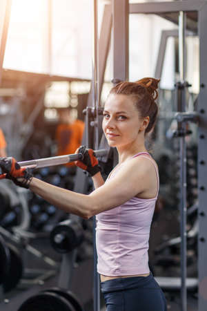Young fitness woman doing squats with barbell in gym.の写真素材