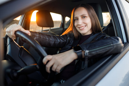 Young woman enjoying driving car at sunset. Travelling by automobileの写真素材