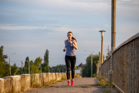 Fitness young woman running on the road in the city. Healthy lifestyle image