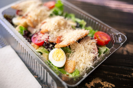Caesar salad in plastic container for food delivery. Takeaway meal for office workerの写真素材
