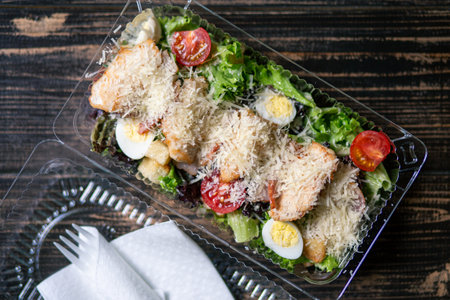 Caesar salad in plastic container for food delivery. Takeaway meal for office workerの写真素材