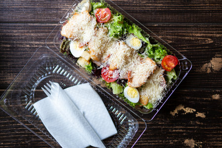 Caesar salad in plastic container for food delivery. Takeaway meal for office workerの写真素材