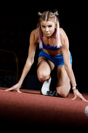 Young sprinter girl on the lane starting her run.