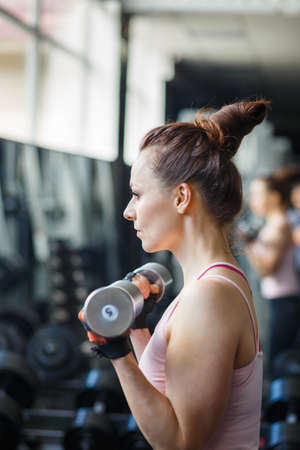 Fitness girl doing exercices with dumbbells for biceps in gymの写真素材