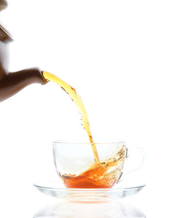 Pouring black tea into transparent cup from teapotの写真素材