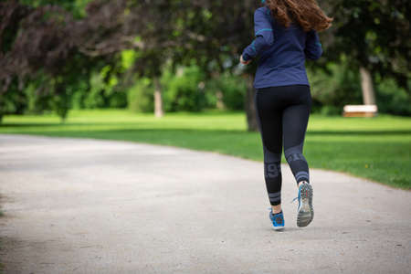 Rear view of running woman in park with copyspace