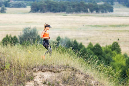Young sporty fitness woman running on the hillの写真素材