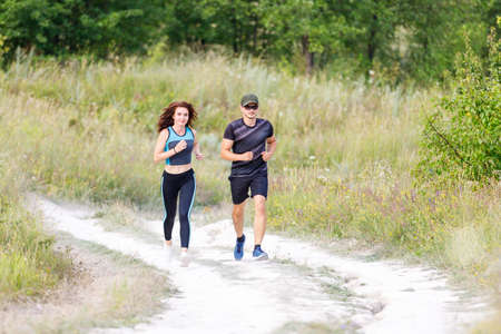 Sporty man and woman run on the country roadの写真素材