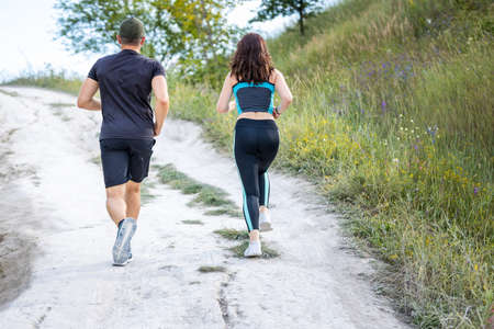 Back view of couple or friends running outdoorsの写真素材