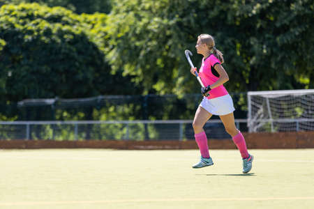 Young girl field hockey player running on pitchの写真素材