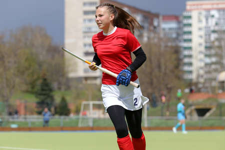 Young field hockey girl player runs with the stickの写真素材