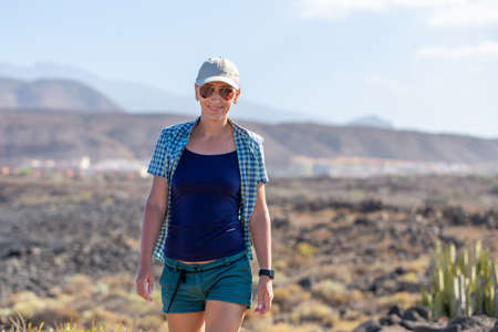 Smiling woman walking on the path in volcanic area